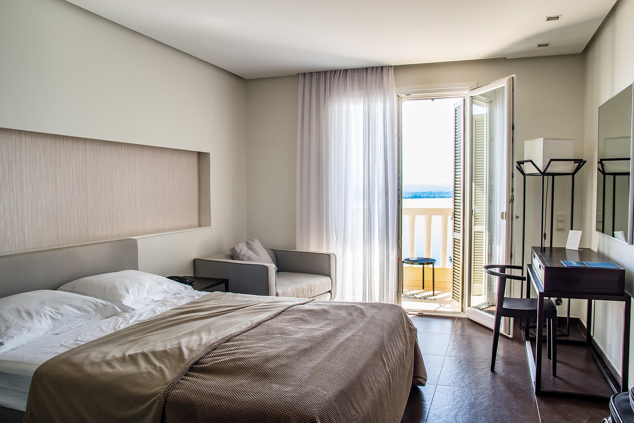 Helles Hotelzimmer mit Doppelbett, Sessel und Fenster zur Straße