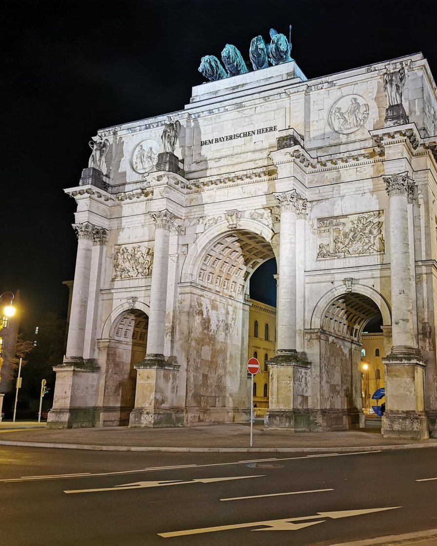 Das Siegestor bei Nacht, davor Lichtspuren des vorbeifahrenden Verkehrs